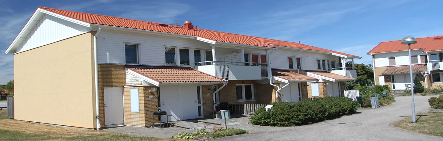 Fasadbild över kvarteret Vävstolen i Sjuntorp. Tvåvåningshus i tegel och vitt trä med uteplatser. 