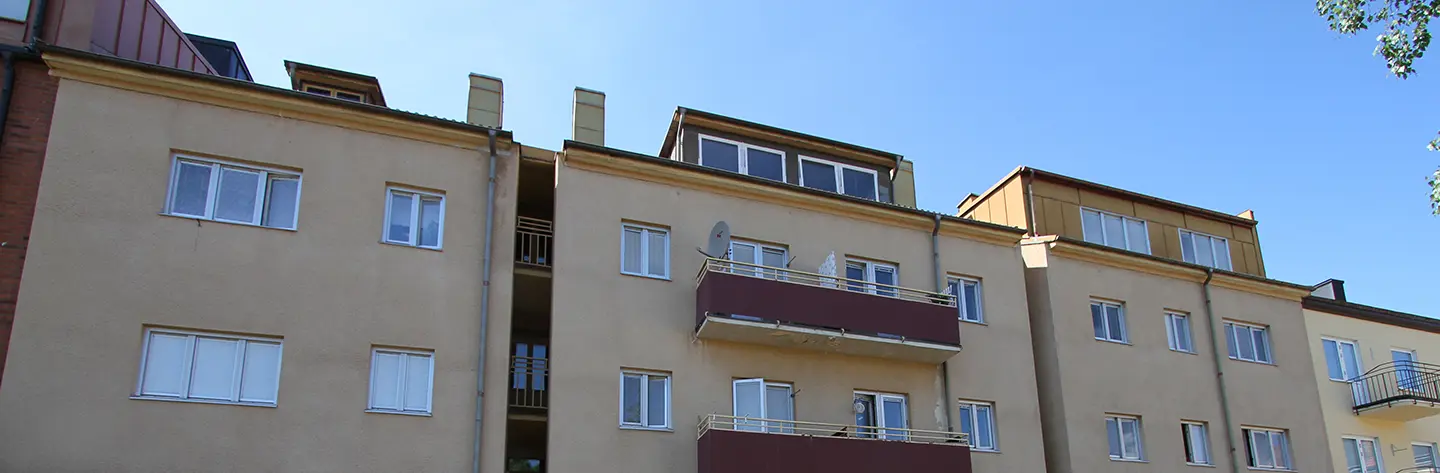 Fasadbild på Österlånggatan i Trollhättan centrum. Ljus fasad med balkonger mot blå himmel