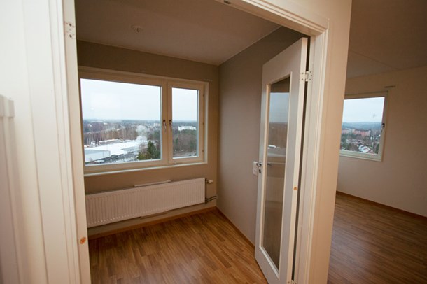 Lägenhet med vita väggar och träfärgad linoleummatta