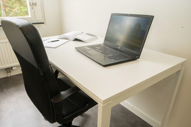 A black chair in front of a white desk in one of the apartments