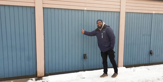 Mohammed på Eidar ger tummen upp utanför en garageport