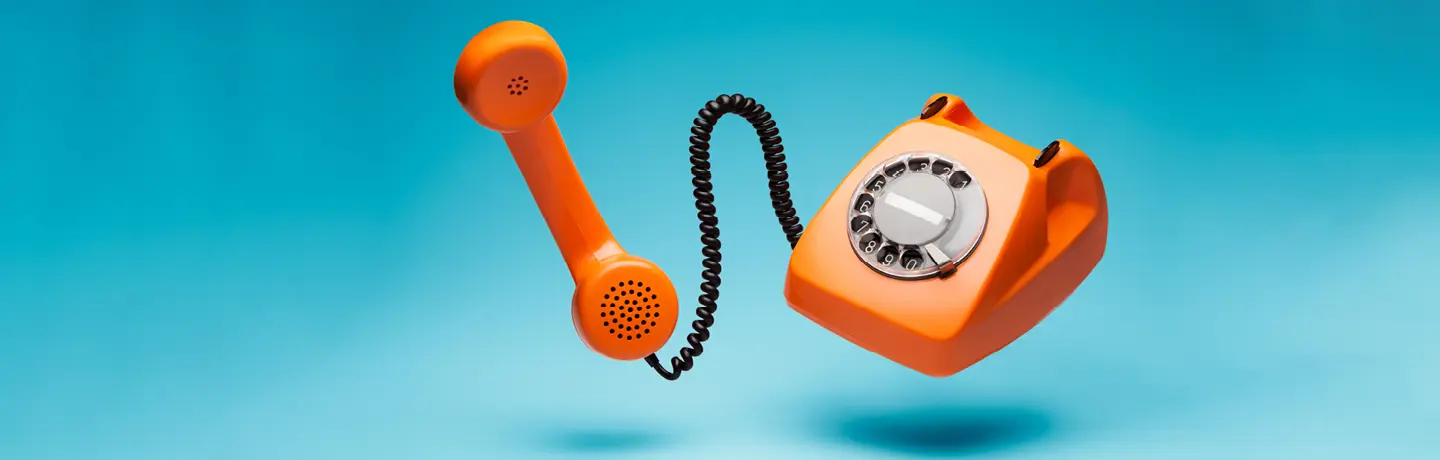 orange klassisk telefon med sladd mot turkos bakgrund