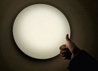 En hand som gör tummen upp framför en lampa i en källare
