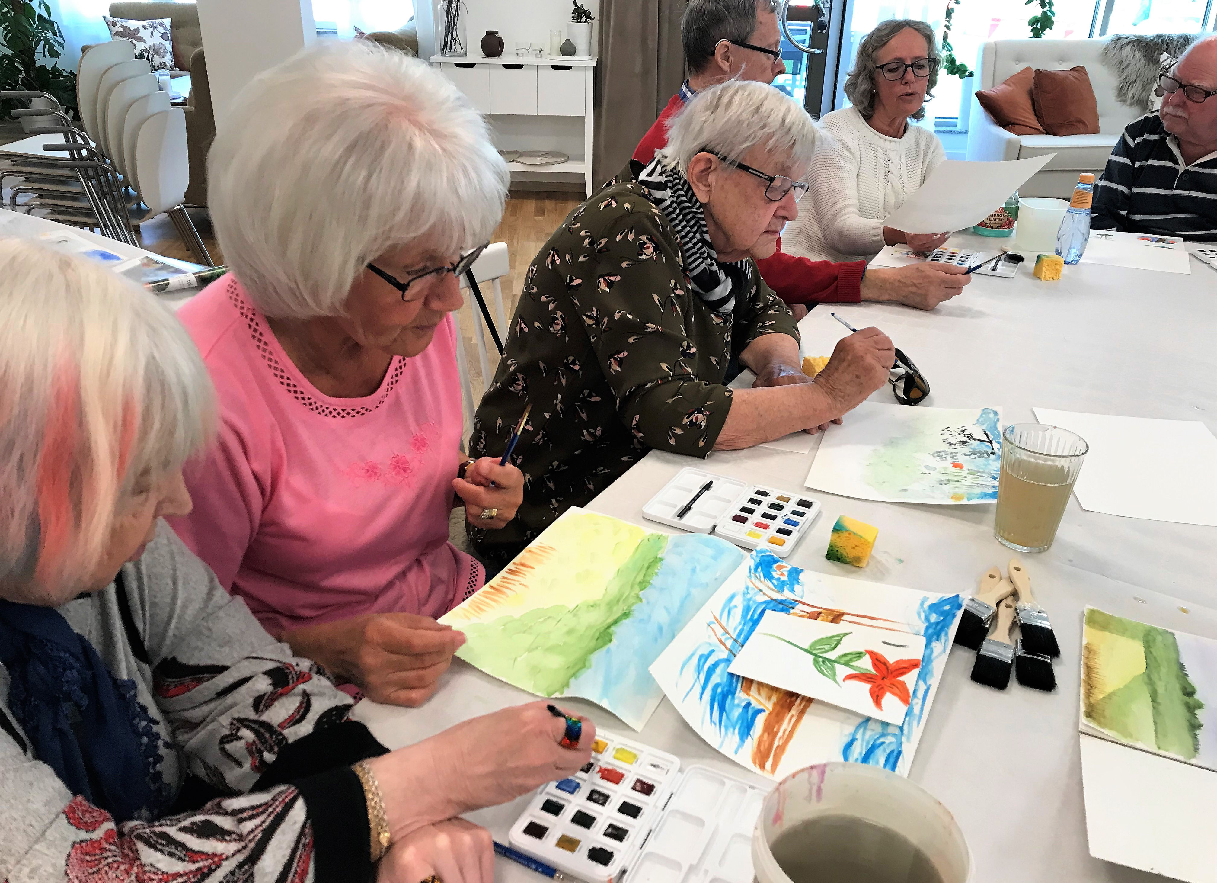 Äldre kvinnor som sitter och målar tillsammans