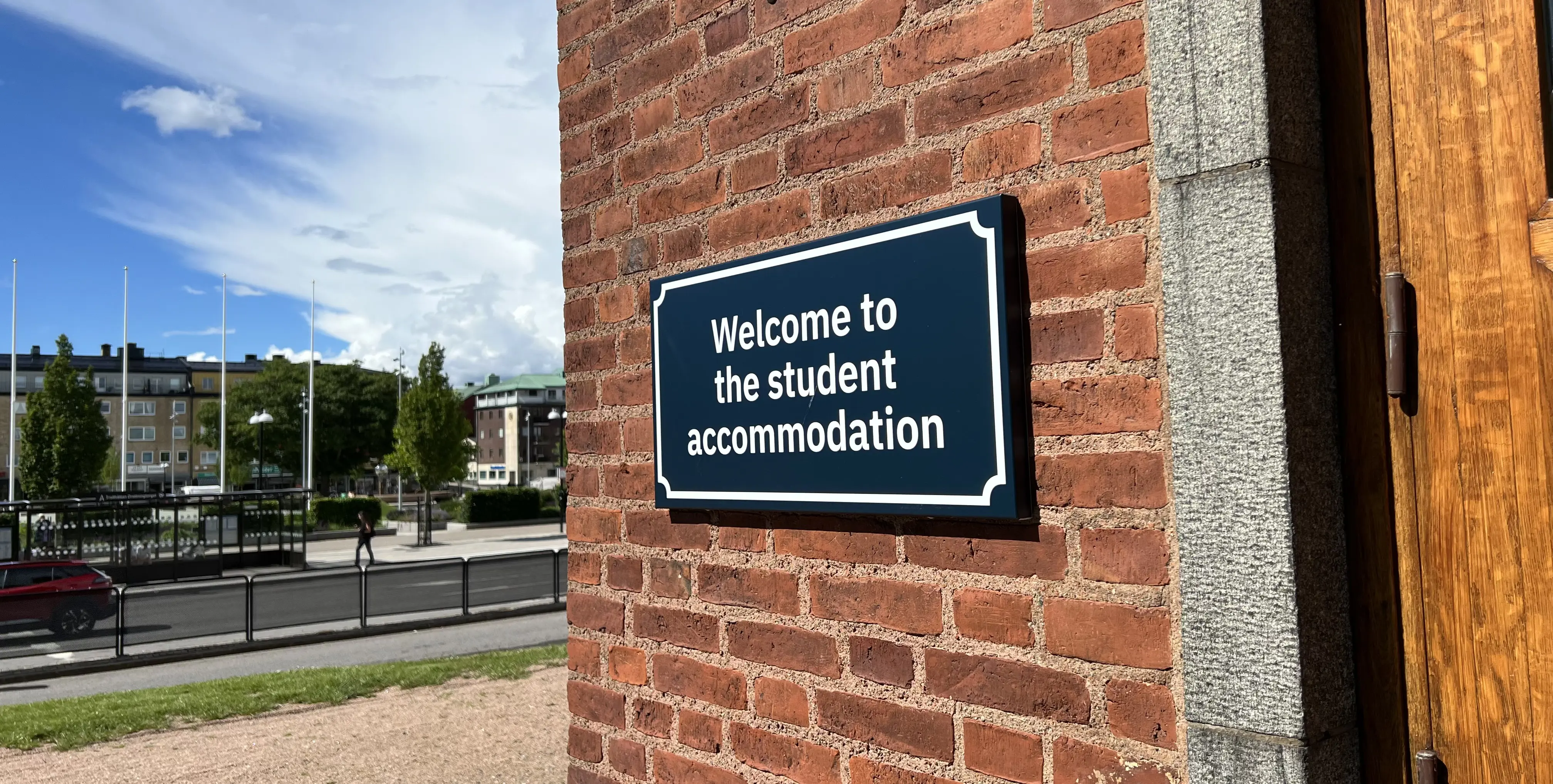 Fasadskylt på studentboendet på högskolans campus, med Drottningtorget i bakgrunden.