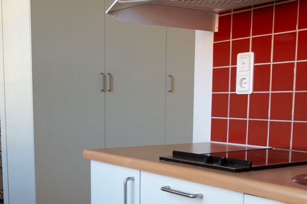 Kök med vita skåp och rött kakel. Material och färger varierar mellan lägenheterna.