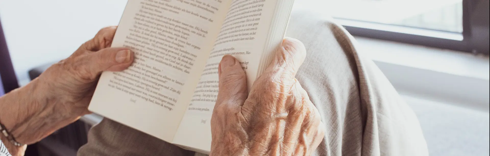 Äldre person som sitter och läser en bok