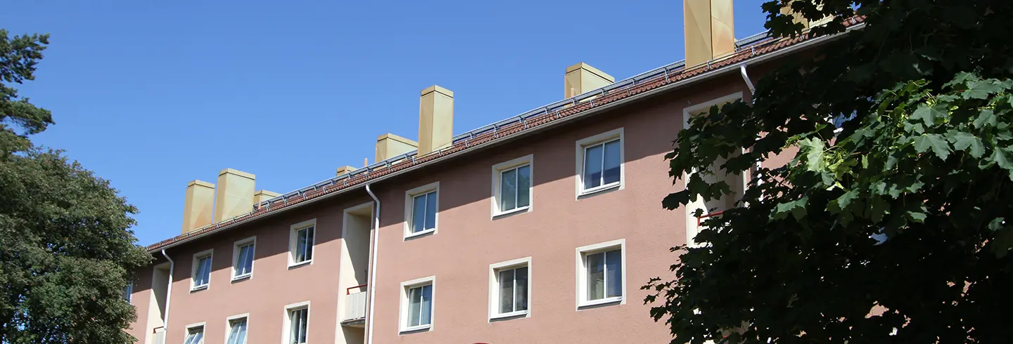 Fasadbild av Flottberget i Trollhättan centrum. Rosa fasad mot blå himmel