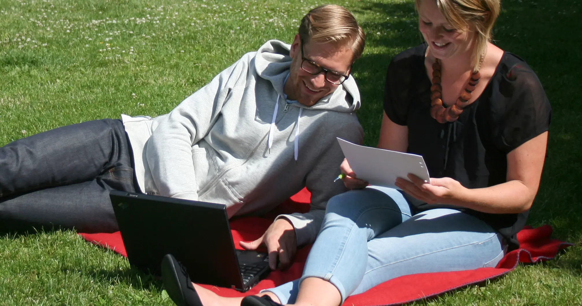 Man och kvinna sitter och jobbar i gräset