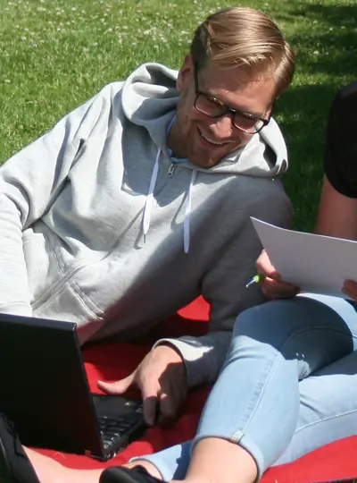 Man och kvinna sitter och jobbar i gräset