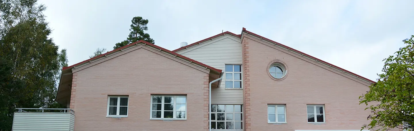 Flerfamiljshus i Skogshöjden i Trollhättan. Tegelfasad i rosa och med liggande vit träfasad.