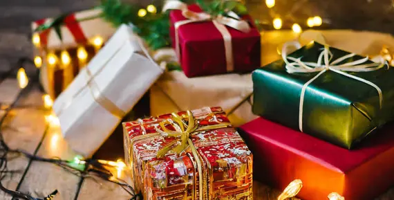 Inslagna julklappar i färgglada färger under en gran