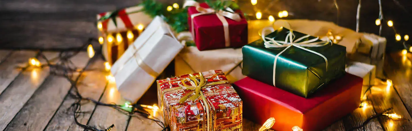 Inslagna julklappar i färgglada färger under en gran