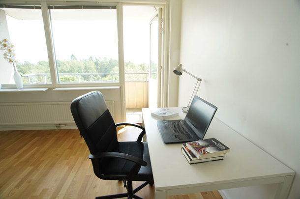 An apartment with white walls, wooden pattern on the floor and a private balcony