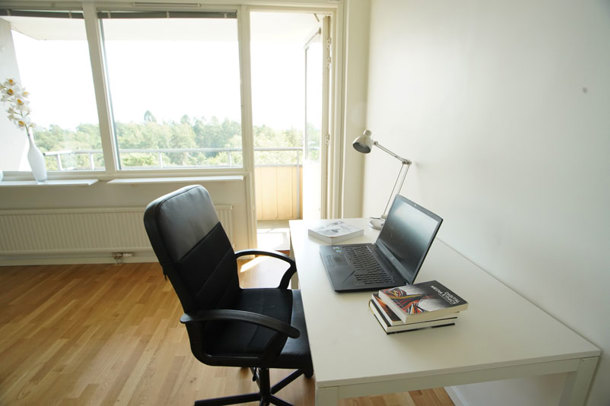 An apartment with white walls and wooden pattern on the floor, and a private balcony.